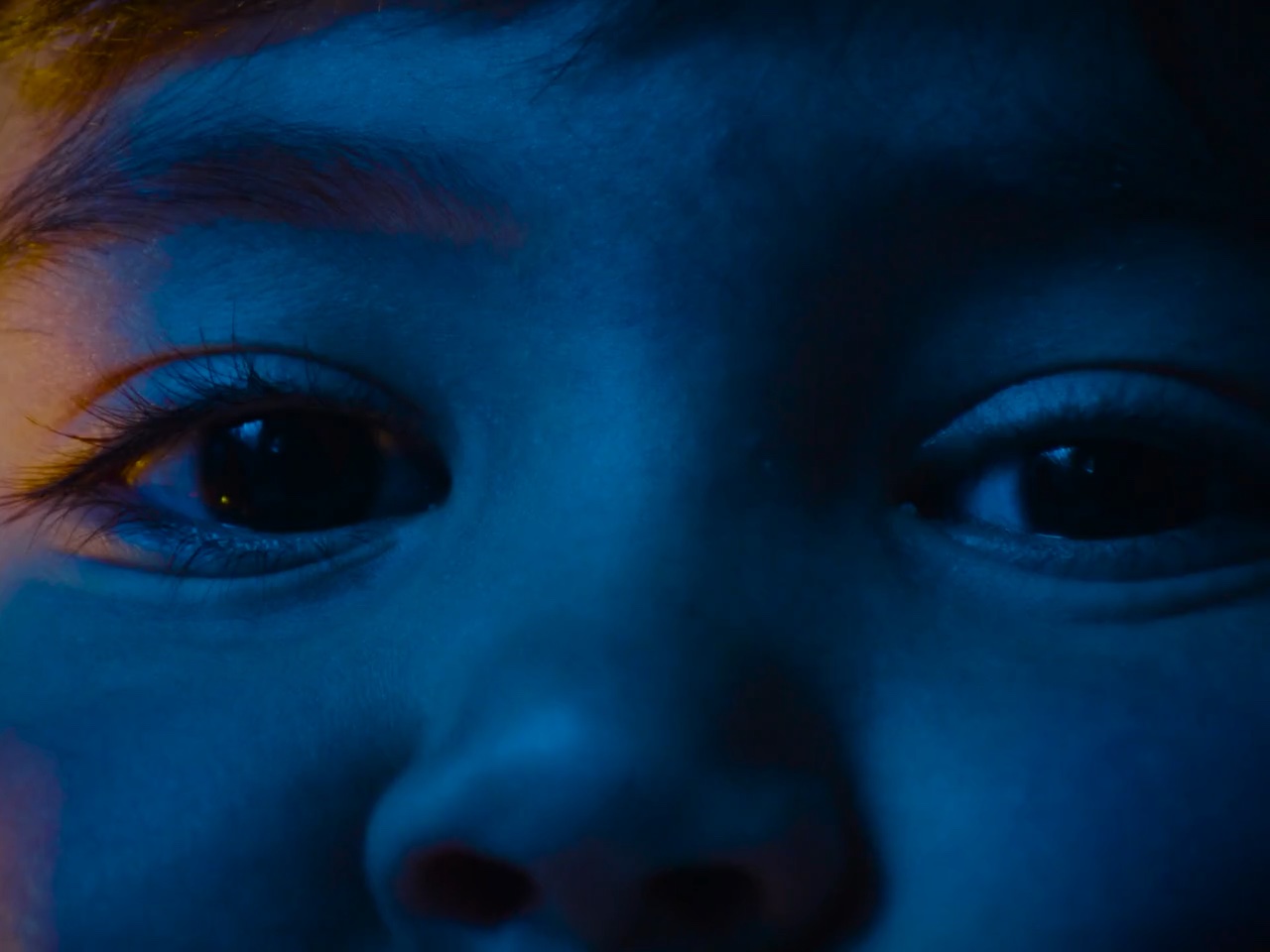 Close-up of a young boy's eyes lit in blue