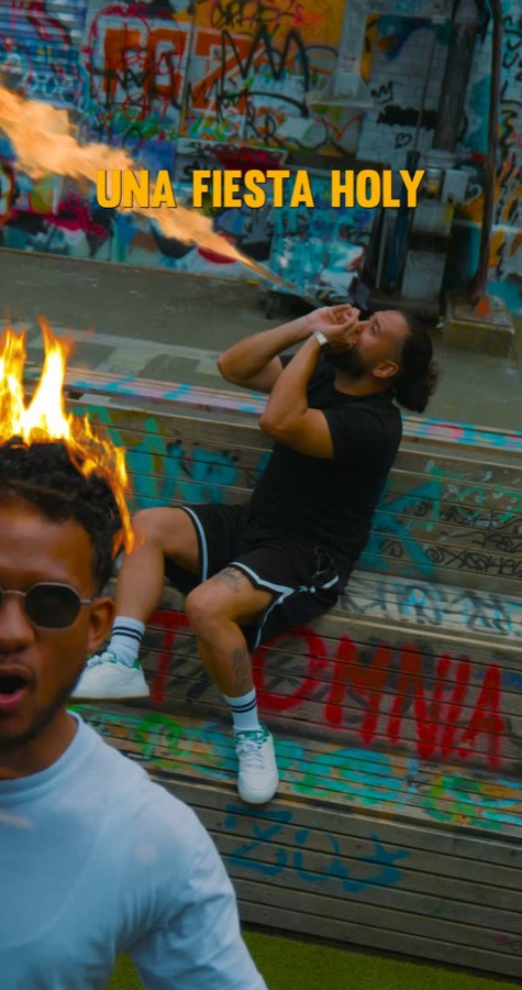 Music video still in front of a graffiti wall