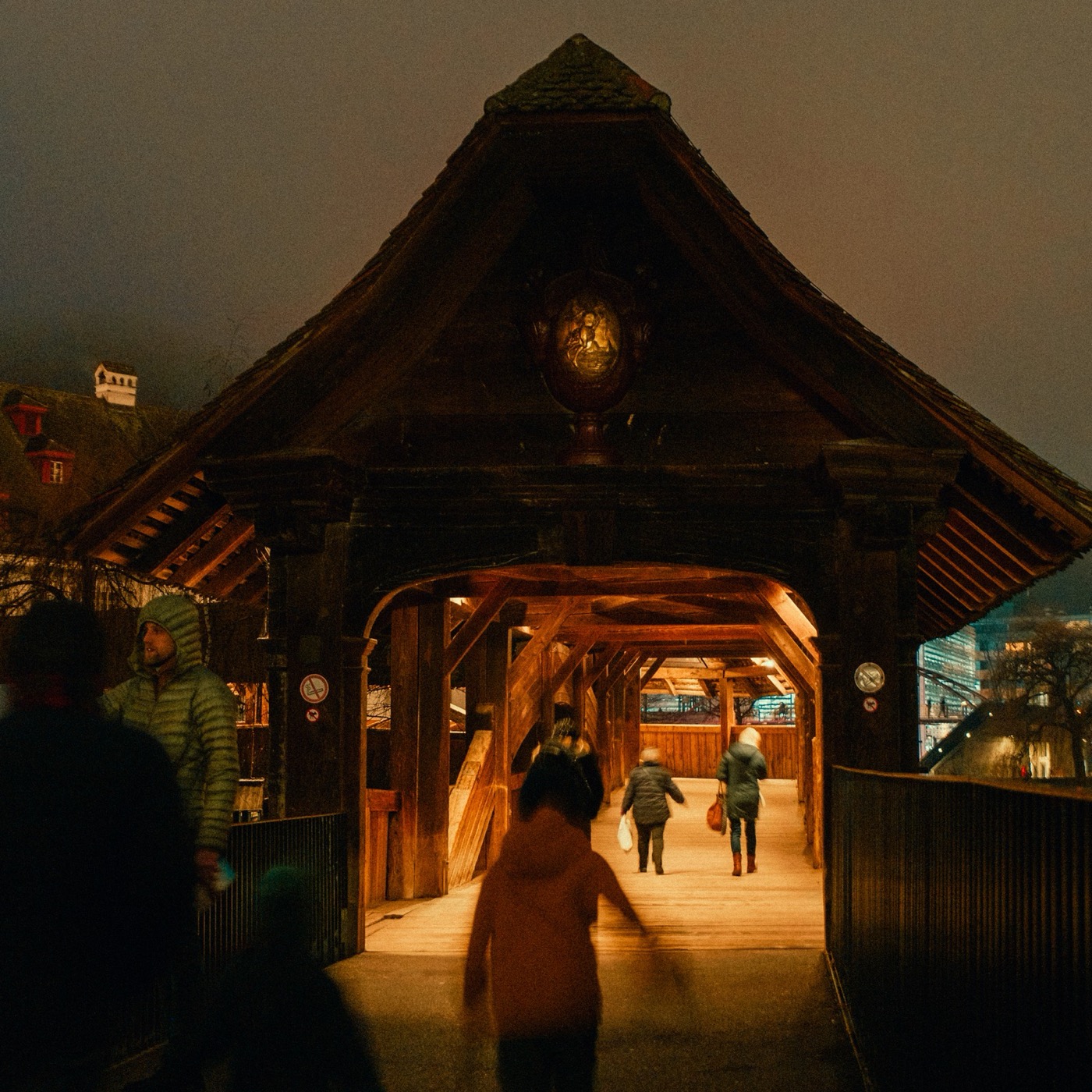 People walking into a covered wooden bridge